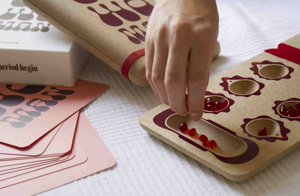 OH WOMAN founders posing while showing the Periodenbrettspiel game setup