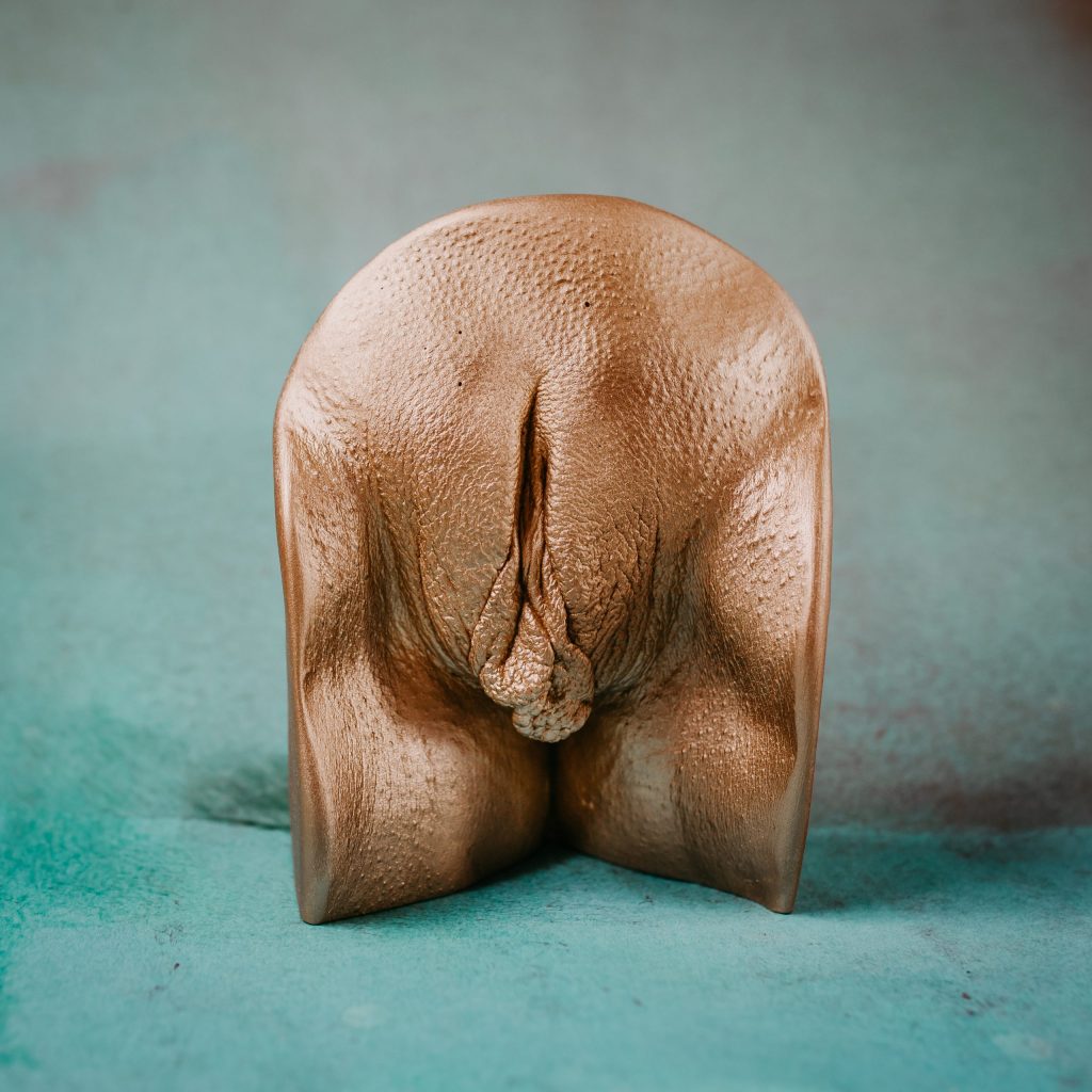 Rounded vulvar statue on a neutral backdrop